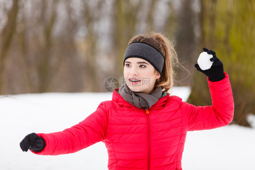 穿着时髦运动服在冬季公园放松运动妇女扔雪球图片