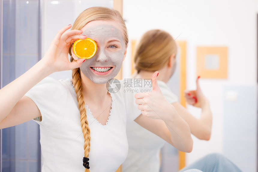 快乐的年轻女子面戴灰色泥罩拿着橙色一块快乐的年轻女子面戴罩抱着kiwi图片