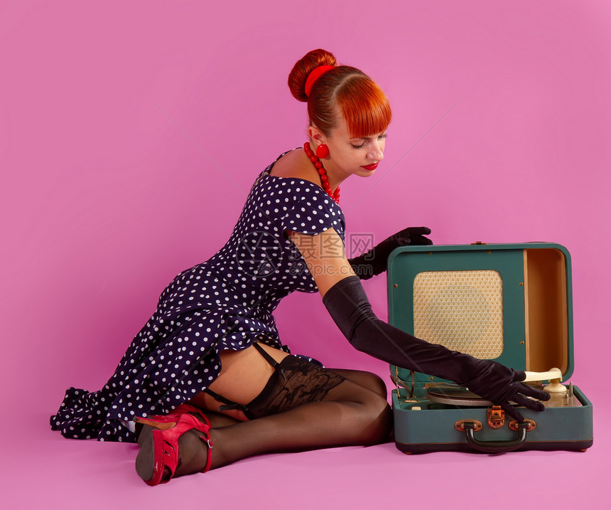 穿着时尚古装和丝袜的年轻女孩正在收听一个古老的留声机唱片图片