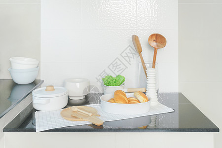 厨房黑柜台顶的面包和白色陶器的托盘图片