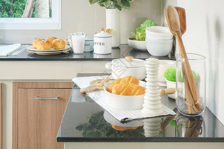 厨房黑柜台顶上的面包和白色陶瓷餐具图片