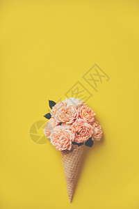 黄底带粉红玫瑰的冰淇淋甜筒夏季最低概念平躺图片