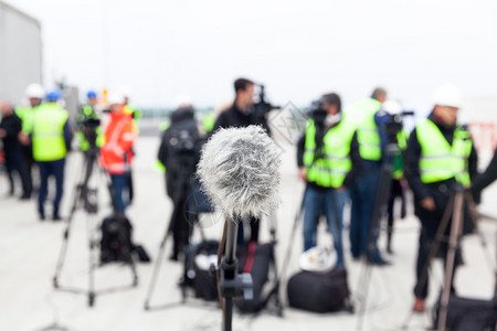 在记者招待会上针对模糊的摄影机操作员和记者进行专注的麦克风图片