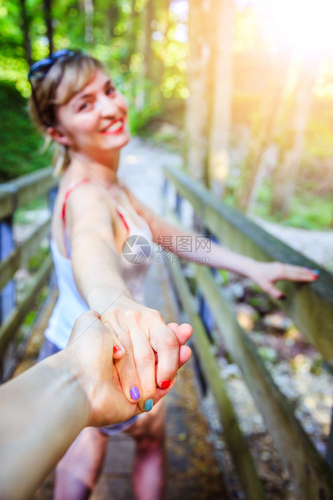 年轻女孩在林地的户外与男友握手图片