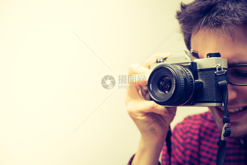 穿红色蓝衬衫的年轻人正在用旧相机拍照图片