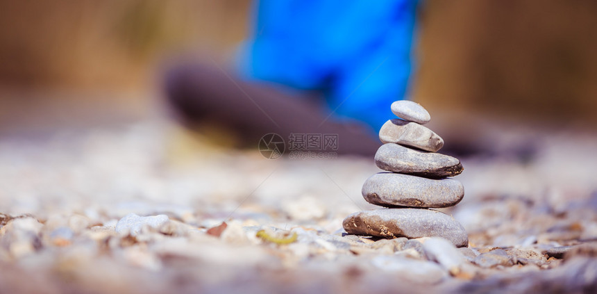 凯恩在石子沙滩上背景中冥想的女人图片