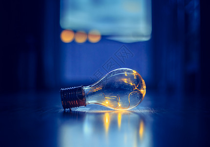 LED灯泡躺在木制地板上是思想和创新的标志是模糊背景中的窗口和灯光背景图片