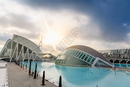 卡拉特拉瓦西班牙巴伦亚市科学城的全景电影院游客在城市科学博物馆旁边参观其背景是黎明时有云和太阳背景