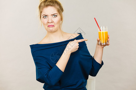 拿着橙汁的恶心金发女人士们不享受新鲜的水果饮料图片