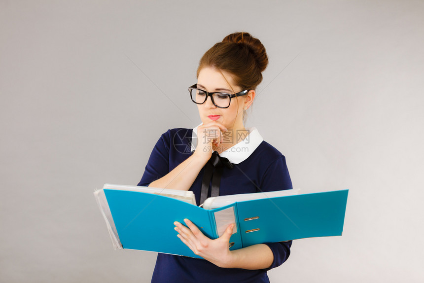 手持蓝文件夹的女办公室工作人员代理年轻优雅的女商人或秘书有文件账单思考面部表情在灰色上的商业和文书工作有件的档案夹图片
