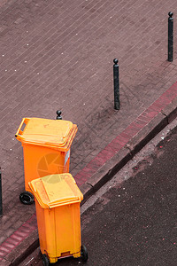 外面街上的塑料橙色轮式垃圾桶等待车的到来图片