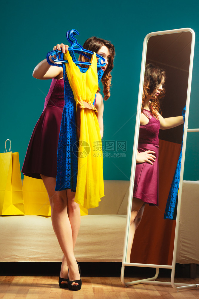 时装和购物女人准备参加派对试着穿衣服迷人的年轻女看着镜子站在服装店里图片