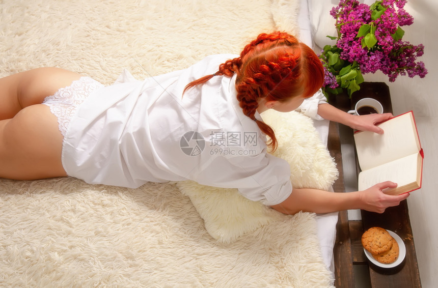 一名年轻女孩穿着短裤躺在床上穿着白男子和衬衫阅读一本书图片