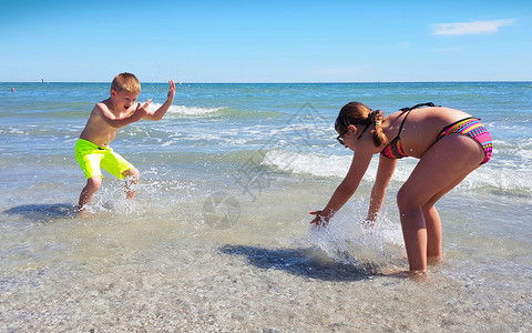 母亲和孩子在海滩上跳跃海岸高清图片素材