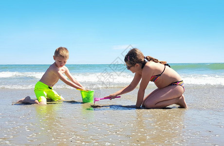 两个孩子在岸边玩耍阳光明媚蓝色高清图片素材