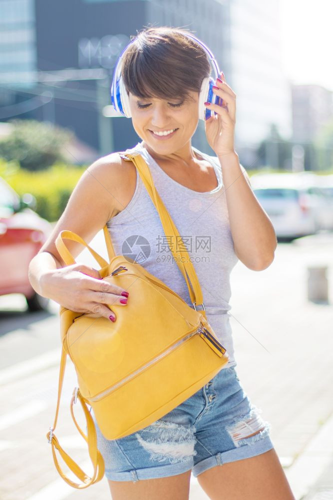 一个快乐女孩在街上用无线耳机监听音乐的肖像图片
