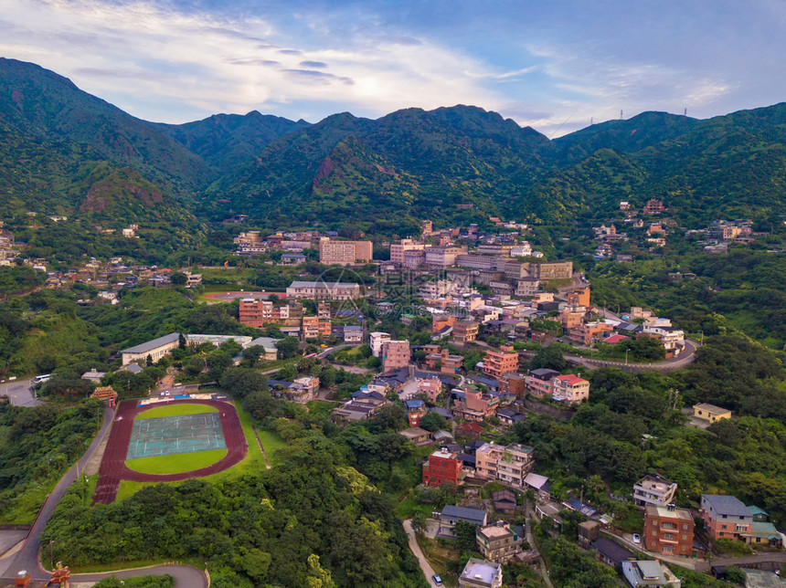 对新北市农村地区山丘上的Jiufen村建筑物和天然绿林的空中观察图片