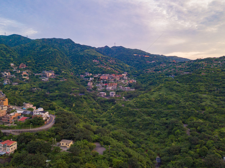 对新北市农村地区山丘上的Jiufen村建筑物和天然绿林的空中观察图片