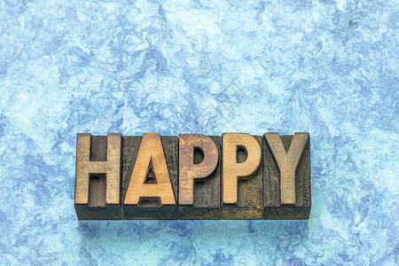 与蓝色树皮纸对比的旧式质印刷木头类型的幸福字词背景图片