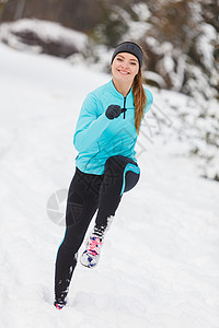 穿着运动服和在雪上奔跑的女孩背景前视树丛冬季运动户外健身康概念图片