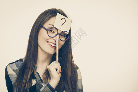 女迷惑思考寻求解决方案纸牌上写有问号眼镜制片厂的可疑年轻女拍摄了刻度图像女在头部上写着问号背景图片