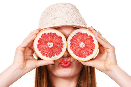 有吸引力的长发女子拿着葡萄水果切片看白微笑女子建议健康食物暑假幸福概念用两半葡萄果柑橘水遮住眼睛背景图片