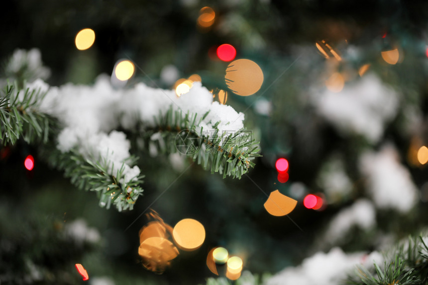 传统人造圣诞树底有灯光和雪图片
