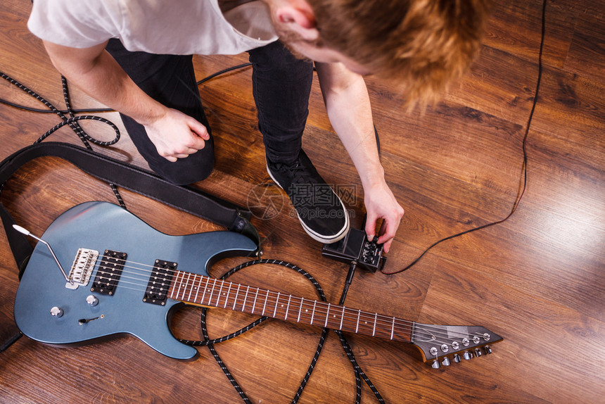 拥有音乐器的人在演播室安装吉他音震箱效果和电缆图片