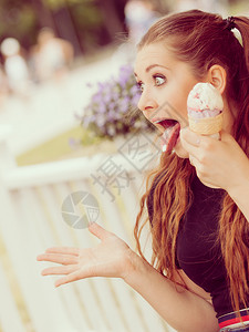 快乐的年轻女子长棕色头发吃冰淇淋享受夏天美丽的气享受甜点图片