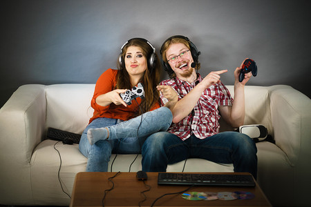 玩射击快乐的情侣通过一起玩电子游戏享受休闲时间背景