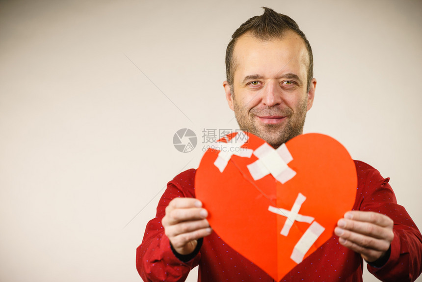 治愈的爱情人节概念笑着的成年人用石膏拿着红心的成年人男愈合关系图片