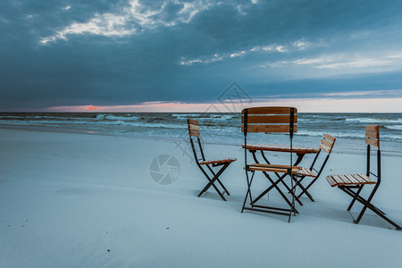 沙滩上美丽的放松场所日落时的木制椅子和桌沙滩上的放松场所图片