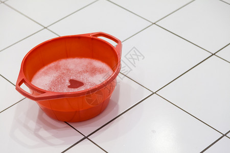 装满洗涤剂或肥皂和水的红碗放在瓦式地板上满洗涤剂和水的红碗图片
