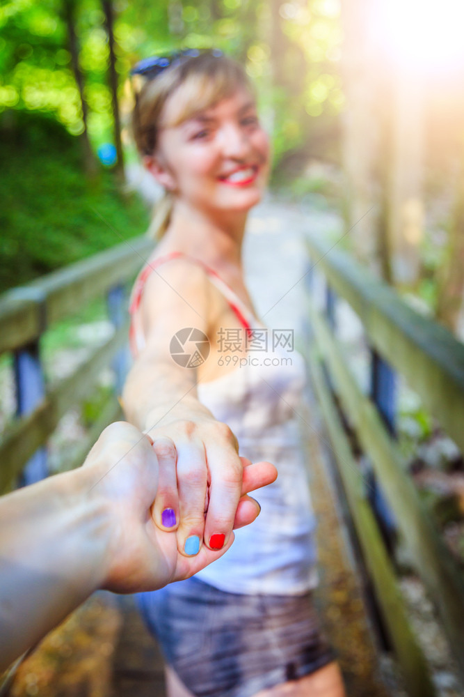 年轻女孩在林地的户外与男友握手图片