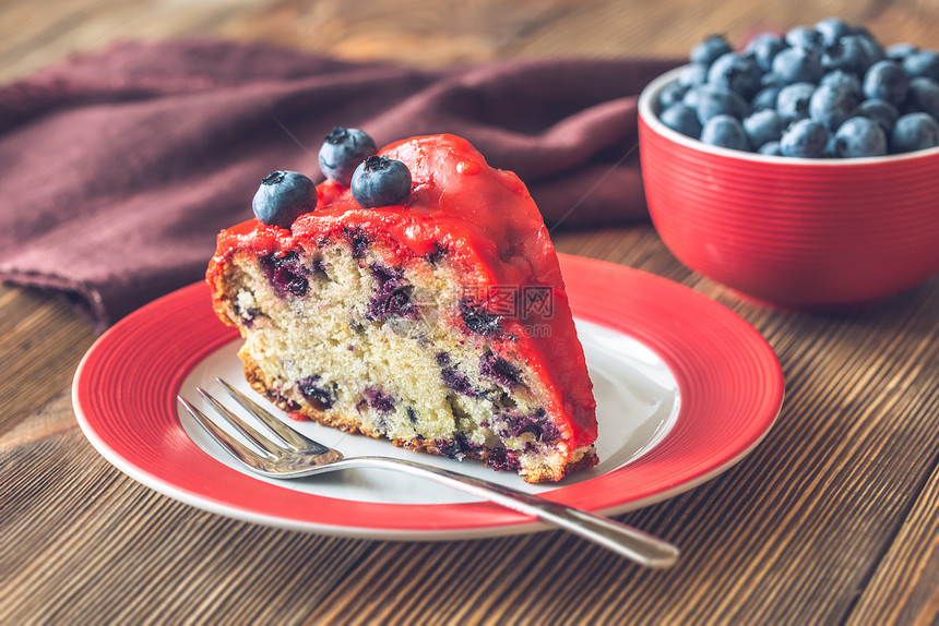 一块小蛋糕蓝莓在板盘上木背景图片