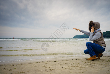 休闲和在海滩上行走的妇女在自然中与水位相近的女旅游者秋寒季日在大自然中与水站相近的女旅游者秋冬季在冷日背景图片