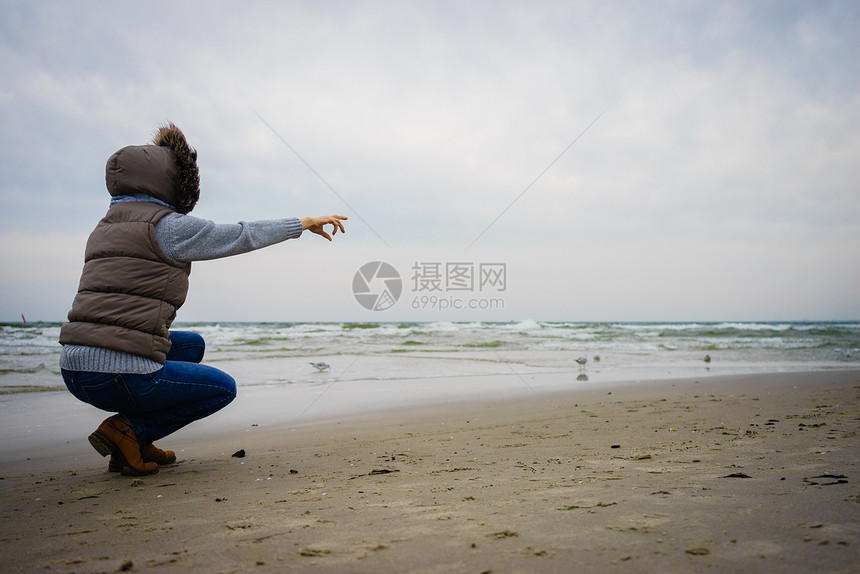 休闲和在海滩上行走的妇女在自然中与水位相近的女旅游者秋寒季日在大自然中与水站相近的女旅游者秋冬季在冷日图片