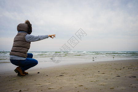 休闲和在海滩上行走的妇女在自然中与水位相近的女旅游者秋寒季日在大自然中与水站相近的女旅游者秋冬季在冷日背景图片