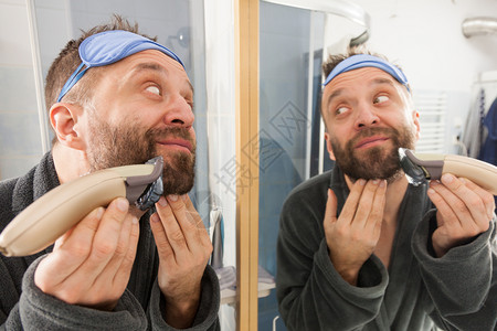 成人男子用电动刮胡刀子背景图片