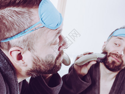 成人男子用电动刮胡刀子背景图片