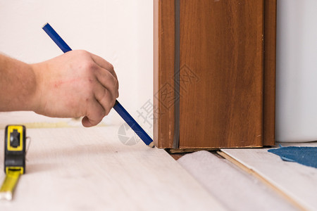使用标尺和铅笔测量地板的建筑工人测量地板家庭翻新概念人测量地板图片