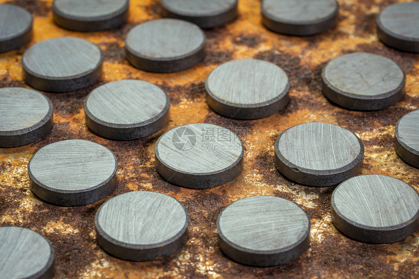 一组小圆形陶瓷发酵磁铁对生锈金属板的顶部视图图片