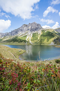 山地景观落岩脉清水湖花朵多彩和蓝云天空图片