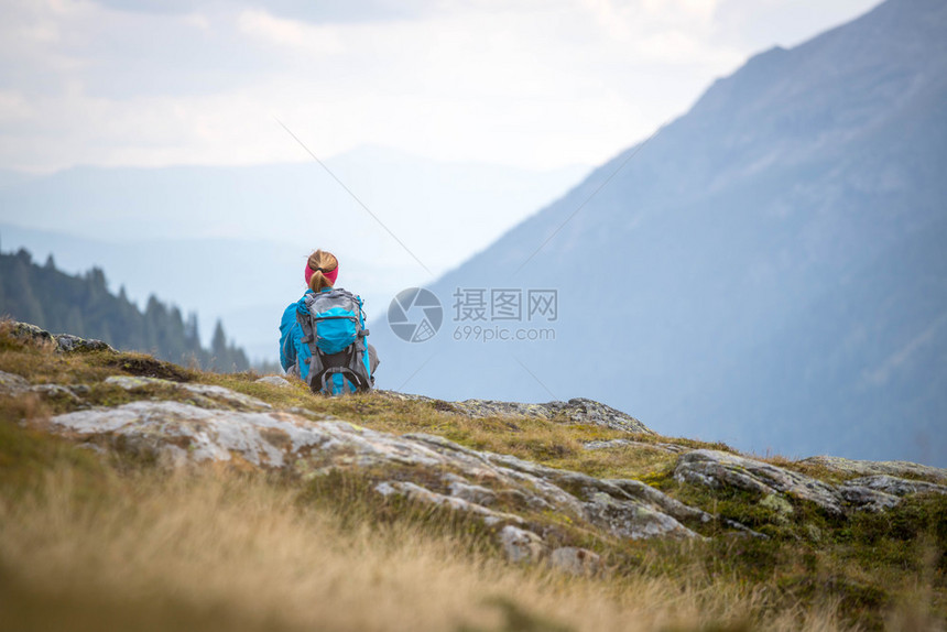 身穿运动服和背包的妇女坐在石土地上山享受风景图片