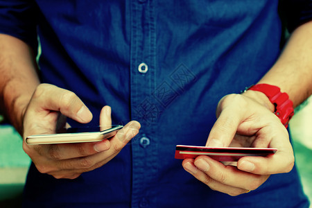 年轻人持有信用卡在网上购物时使用智能电话在线支付概念图片