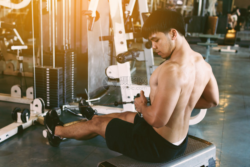 年青的亚洲运动员在室内健身房修肌肉时仍然举重图片