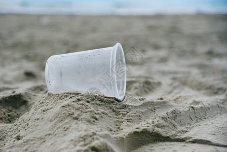 海洋垃圾和塑料杯在岛上沙海洋垃圾污染的环境问题图片