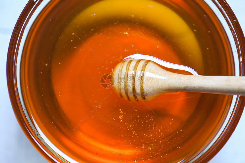 蜜蜂从一个木制蜜花瓶里滴落的蜂水在罐子里关闭顶端的视野图片