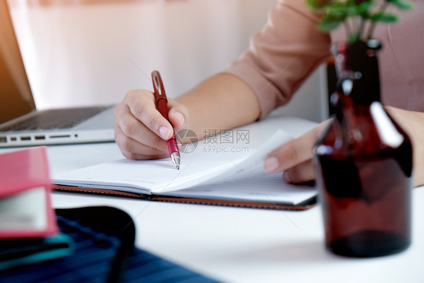 在课堂上时坐在桌边用笔记本电脑和学习的年轻妇女图片