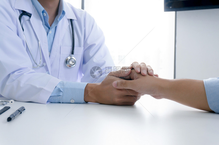 医生持有病人和shands并安抚他的男病人帮助手的概念图片